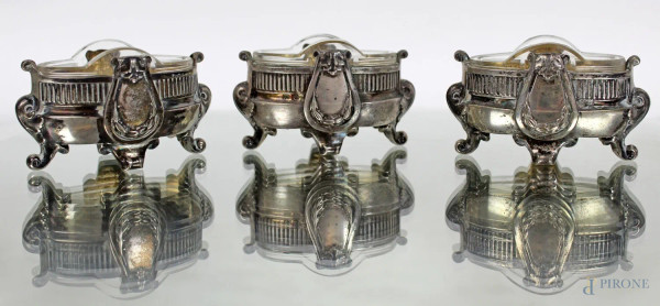 Lotto composto da tre salierine in argento sbalzato e cesellato, con vaschette in cristallo, poggianti su quattro piedini a ricciolo, altezza cm 4