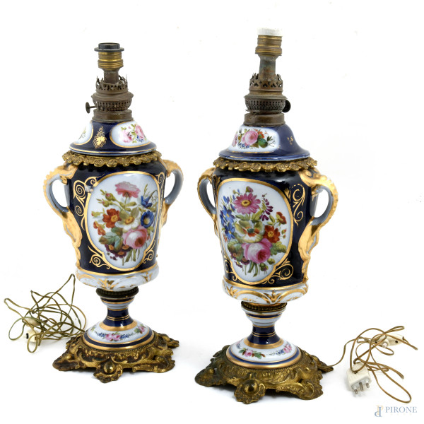 Coppia di vasi biansati in porcellana nei toni del blu, del bianco e dell'oro decorati a motivi floreali con inserti bronzei. Montati a lampada da tavolo. XX secolo, altezza cm 51, (segni di usura, cadute di doratura, scalfiture, difetti)
