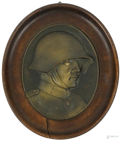 Placca in bronzo ad assetto ovale in metallo raffigurante soldato con elmetto, cm 18x15, firmato P.Kramer, entro cornice in legno.