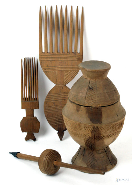 Lotto di quattro oggetti in legno, composto da: un contenitore, due pettini e un fuso per filare, altezza max cm 21, arte africana, XX secolo, (difetti).