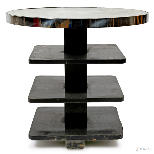 Tavolinetto in legno laccato nero in stile Gio Ponti con piano circolare in vetro ornato da raffigurazione argentata di arciere. Corpo a triplice scaffalatura, XX secolo, cm 63,5x70,5, (difetti)