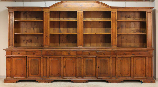 Libreria in legno dolce, parte superiore a giorno, parte inferiore a otto cassetti ed otto sportelli, XX sec, h. 214x387x48 cm.