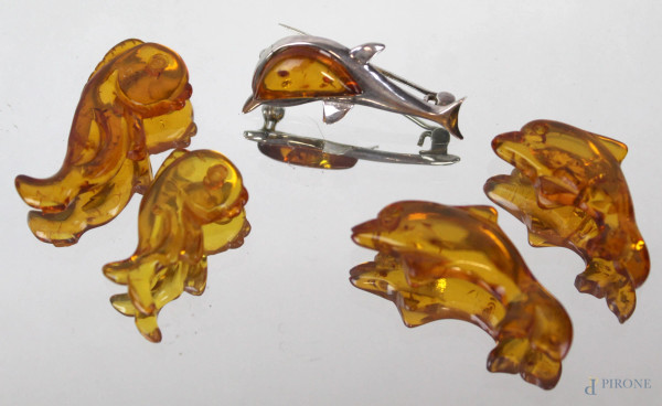 Lotto di due cavallucci marini, due delfini ed una spilla in ambra ed argento, lunghezza max cm 4,5.