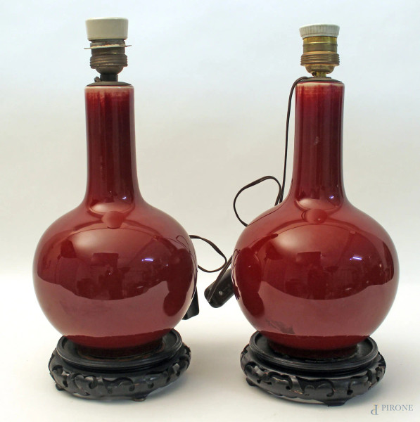 Coppia lampade in porcellana rossa, poggianti su basi in tek, H 28 cm, primi &#39;900.
