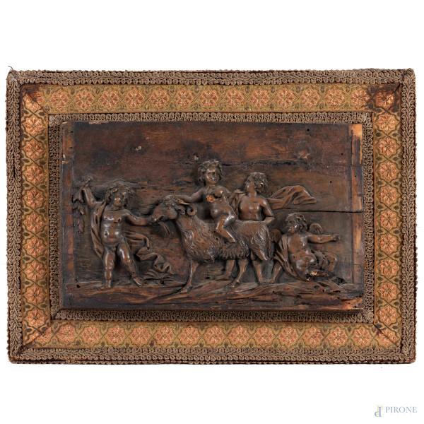 Bassorilievo in legno rappresentante corteo di putti applicato su pannello rivestito in tessuto, XIX secolo, cm 26,5x37, (segni di usura, difetti)