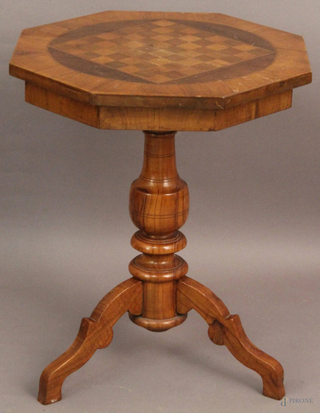 Tavolinetto di linea ottagonale in noce poggiante su colonna e tre gambe, piano a scacchiera XX sec, h. 63x52 cm.