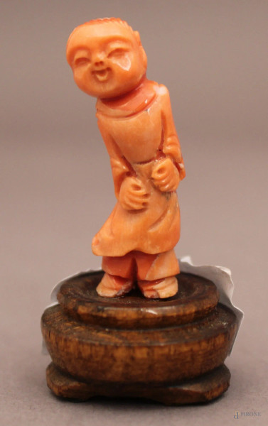 Bambino, scultura in corallo poggiante su base in legno, H 3,5 cm.