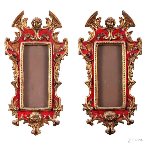 Coppia di cornici in legno dipinto, dorato e intagliato dal profilo sagomato, XX secolo, cm 62x32; luce cm 31x12, (segni di usura, sbeccature, difetti)