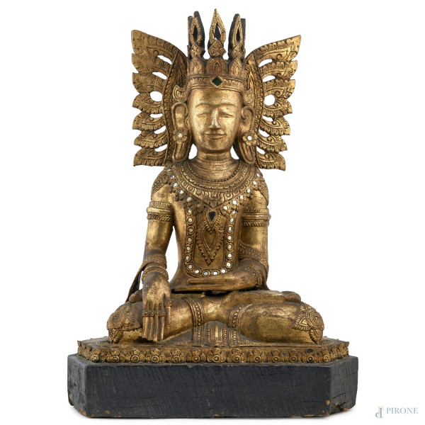 Buddha, scultura in legno dorato e intagliato con inserti in vetro e vetro colorato. Birmania, XX secolo, altezza cm 63, (scalfiture, felature, segni di usura, cadute di doratura)