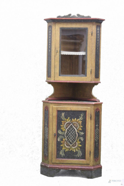 Angoliera a due corpi in legno laccato e dipinto, parte superiore ad uno sportello a vetro, parte inferiore ad uno sportello, h. 198 cm.