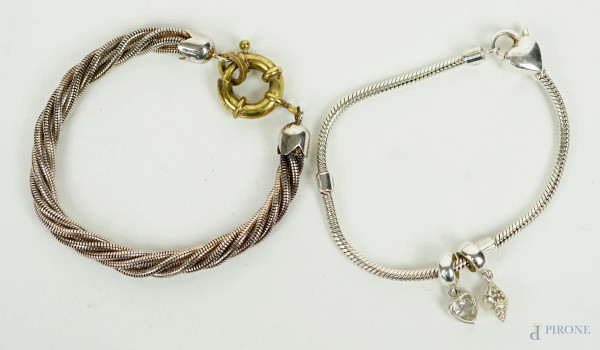 Due bracciali in argento ad intreccio e con ciondoli a forma di cuore e conchiglia, lunghezza max cm 20, (segni del tempo).