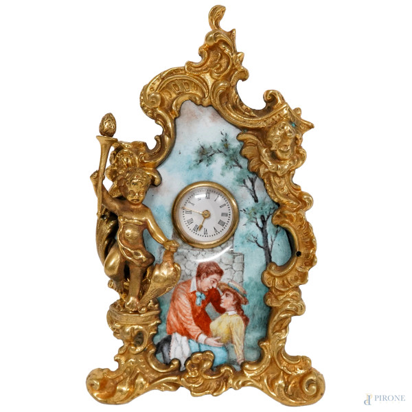 Piccolo orologio da tavolo in bronzo dorato e smalto policromo, decorato con scena galante e un putto, Vienna, XIX secolo, quadrante circolare in smalto bianco, cm 12x7 (difetti e meccanismo da revisionare)