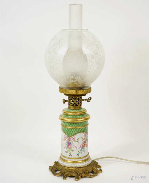 Lampada in porcellana bianca e verde, decori policromi a fiori e festoni, base e finiture in metallo dorato, paralume in vetro molato, XX secolo, h cm 56 (difetti)