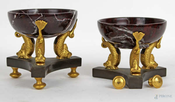 Coppia di vaschette in marmo sorrette da delfini mitologici in metallo dorato, poggianti su basi a tripode in metallo brunito, altezza cm 8,5, (mancante un piedino)