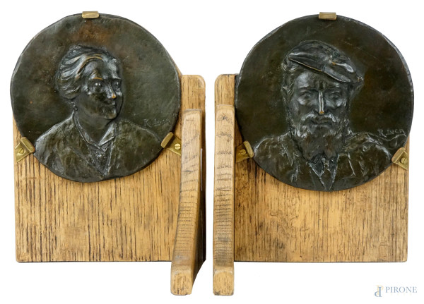 Coppia di fermalibri in legno con placche a bassorilievo in bronzo raffiguranti gentiluomo e gentildonna , cm 22,5x17,5x15, firmati R.Luca, (segni del tempo).