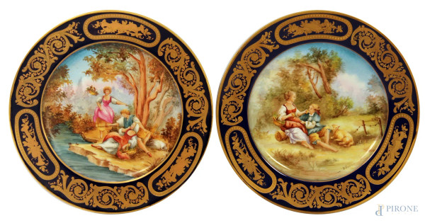 Coppia di piatti in porcellana con medaglioni centrali dipinti a decoro di paesaggi e scene galanti, fascia blu cobalto e oro, marcata Maissen, diam. 25 cm.