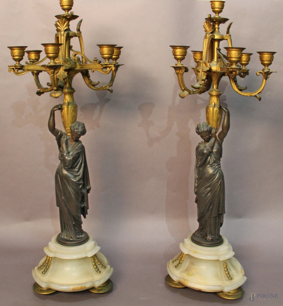 Coppia di candelieri a sei luci in bronzo sorretti da figure, base in onice con piedini ed applicazioni in bronzo, Francia, inizi XX sec., H 68 cm.