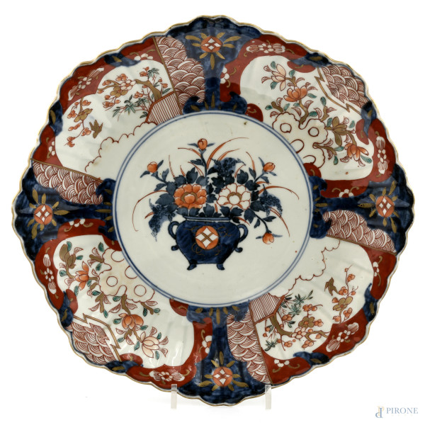 Piatto in porcellana decorata nei toni del bianco, rosso e blu a motivi geometrico-floreali. Cina, XX secolo, diametro cm 32, (segni di usura, graffi, difetti)