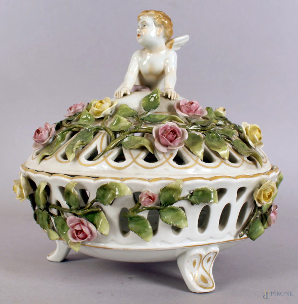 Centrotavola in porcellana traforata con fiori a rilievo, coperchio sormontato da putto alato, altezza 20 cm, (piccoli difetti).