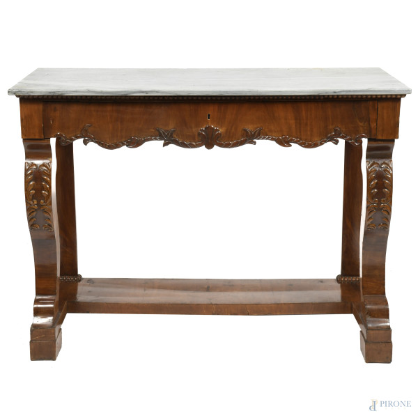 Consolle impiallacciata in noce con piano in marmo e fronte a un cassetto. Gambe anteriori mosse e intagliate, raccordate da pedana. XX secolo, cm 94,5x128,5x55,5, (segni di usura, scalfiture, difetti)