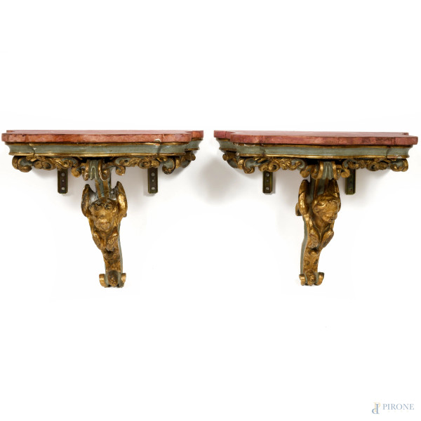 Coppia di consolle da muro in legno intagliato, dipinto e dorato con piano in legno dal profilo sagomato dipinto nei toni del rosso, XX secolo, cm 45x47x29, (difetti)