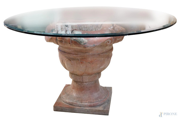 Tavolo di linea circolare, XX secolo, con piano in vetro, base in marmo rosa a forma di vaso, cm h 76, diam. piano cm 140, (sbeccature e lievi difetti)