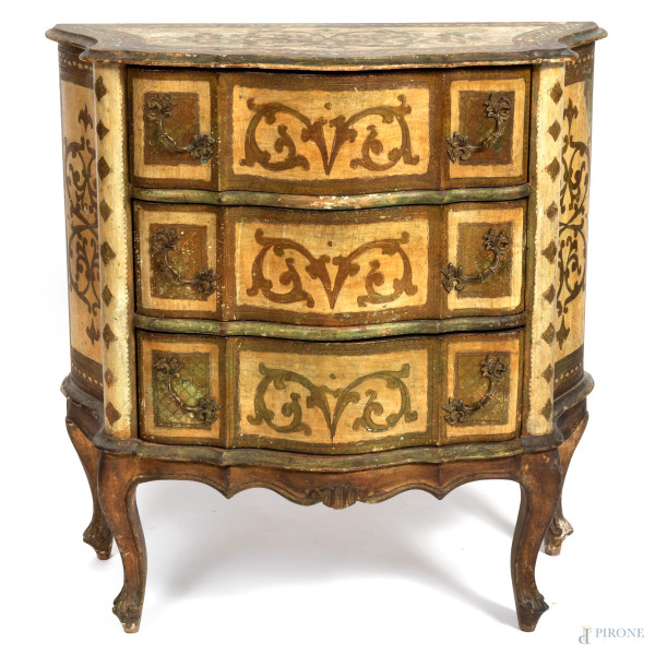 Comodino in legno intagliato, dipinto e laccato con fronte mosso scandito a tre cassetti e gambe mosse, XX secolo, cm 78x76x36, (segni di usura, difetti, scalfiture)