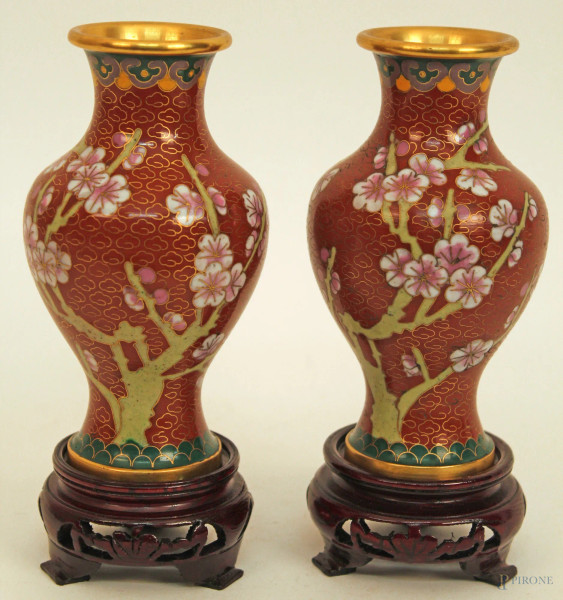 Coppia di vasi cloisonn&#232; a decoro di fiori con fondo rosso, poggianti su basi in tek, h. 12 cm.