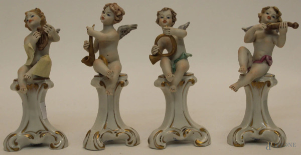 Lotto composto da quattro putti musicanti in bisquit, poggianti su basi in porcellana Capodimonte, H 12 cm.