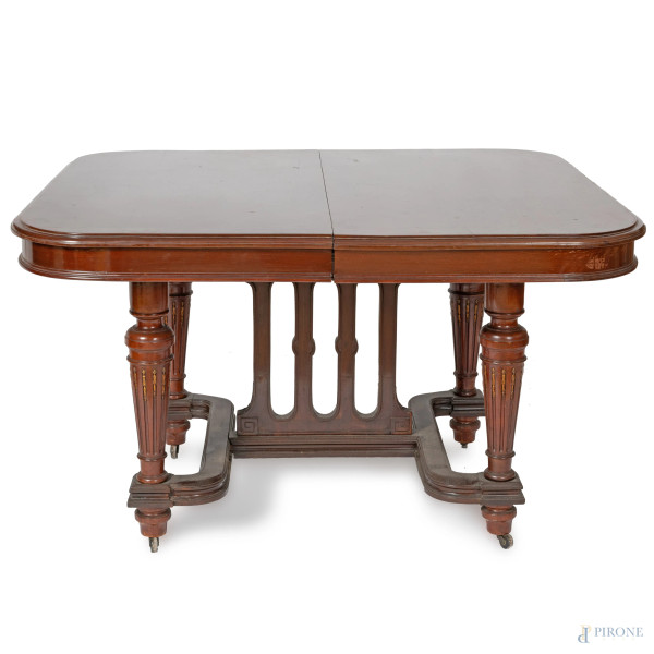 Tavolo in mogano con quattro gambe tornite, munite di rotelle e raccordate da elemento a balaustra, inizi del XX secolo, cm 78x128x113. Corredato di 2 prolunghe, cm 60,5 cad., (segni di usura, graffi, scalfiture)