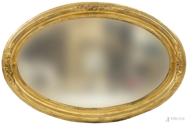 Specchiera ovale in legno e stucco dorato, fine XIX-inizi XX secolo, profilo interno perlinato seguito da fascia modanata ornata da fregi floreali a rilievo, cm 66x98, (difetti)