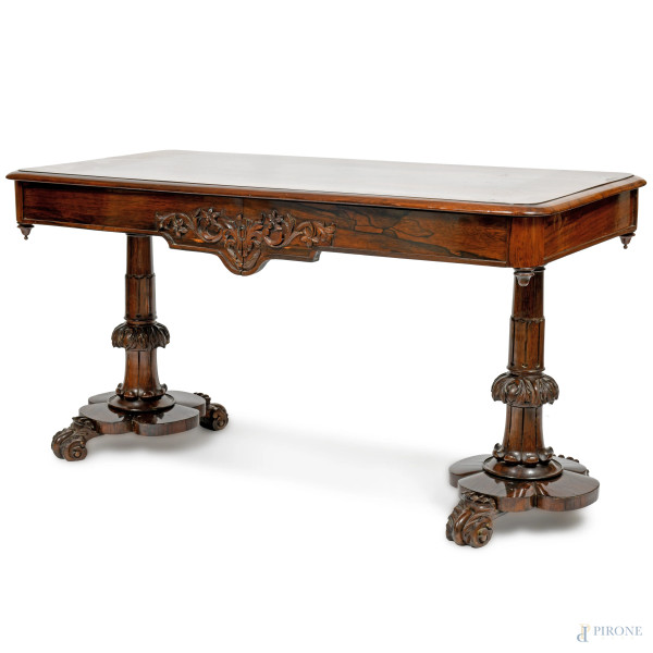 Tavolo scrittoio in legno scuro con piano rettangolare a fascia liscia e riserva centrale intagliata a motivi fogliacei. Gambe tornite arricchite da terminazioni fogliacee a ricciolo, XX secolo, cm  73x137x62,5, (graffi, segni di usura, scalfiture)