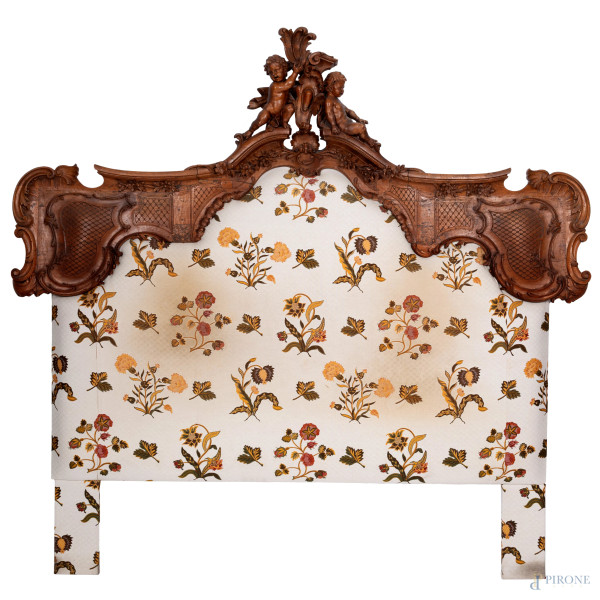 Testata da letto in legno intagliato con elemento apicale con putti, XX secolo, cm 187x197, (segni di usura, scalfiture, fori di tarlo, difetti)