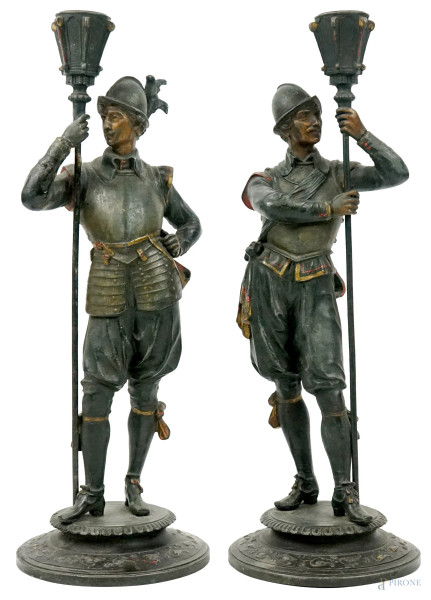Due candelieri in metallo brunito e dorato raffiguranti soldati, cm h 37, XX secolo, (difetti).
