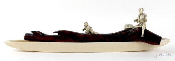 Okimono giapponese in avorio e legno, raffigurante uomo con cesta ed un bambino posati su un ramo di legno a sua volta posato su una barca in avorio, altezza cm. 8x30,5, Giappone, periodo Meiji.