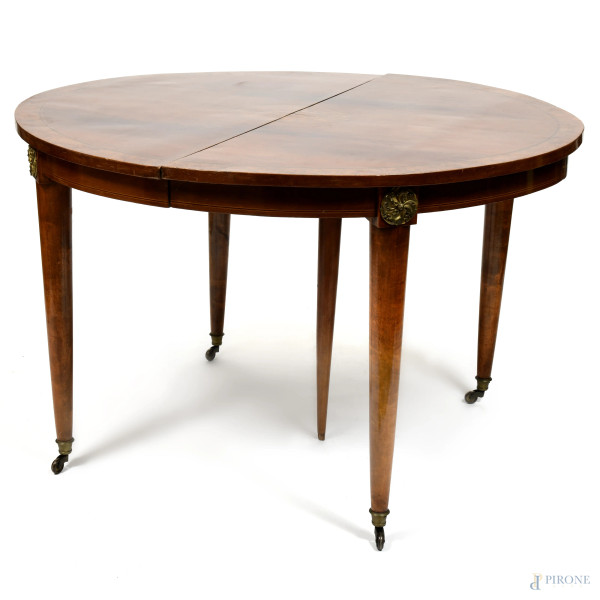 Tavolo ovale  allungabile in legno impiallacciato e intarsiato in varie essenze. Gambe munite di inserti bronzei e rotelle, XX secolo, cm 80x127x114, (segni di usura, scalfiture, difetti)