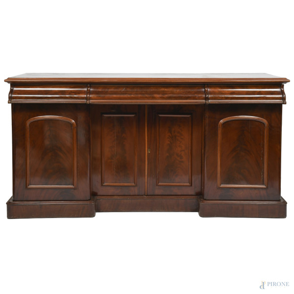 Bassa credenza in legno impiallacciato in piuma di mogano con tre cassetti sormontanti vano a doppio sportello affiancato da coppia di ante. XX secolo, cm 96x183,5x67, (segni di usura, scalfiture, difetti)
