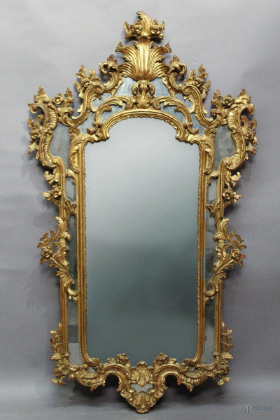 Specchiera di linea centinata in legno intagliato e dorato, H 118 cm, primi 900.