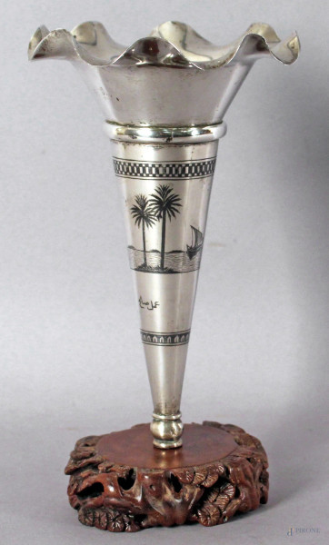 Vasetto in argento inciso raffigurante paesaggio arabo, poggiante su base in teak, altezza 21 cm.