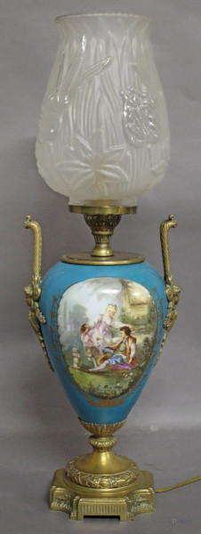 Lampada in porcellana dipinta con due medaglioni raffiguranti scena galante e fiori, base ed anse in ottone, completa di globo in vetro, Francia fine XIX sec., H 63 cm.