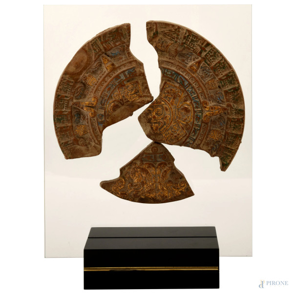 Riproduzione di grande medaglione di ispirazione azteca montanto su lastra in vetro poggiante su base in metallo laccato nero, XX secolo, cm 44x32 (difetti)
