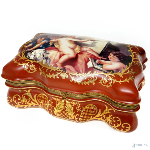 Portagioie in porcellana dal profilo mistilineo, decorato a racemi dorati e in policromia con scena raffigurante putti, XX secolo, cm 18x34,5x20,5, (difetti)