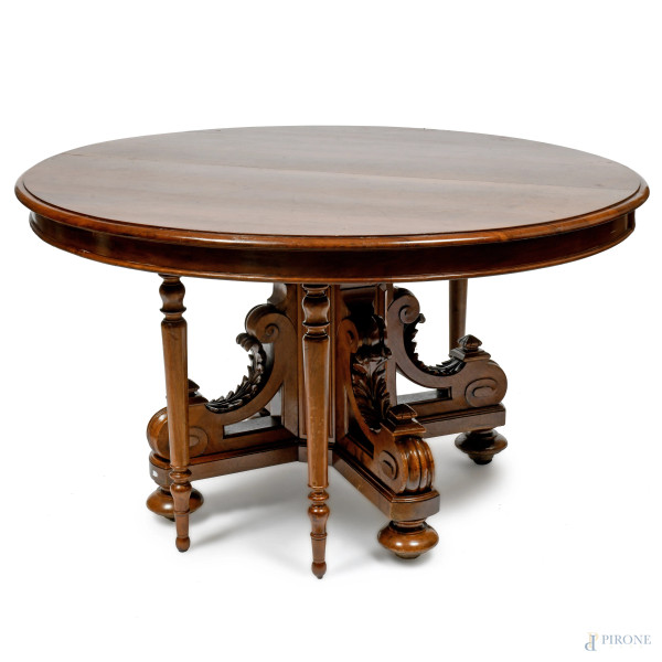 Tavolo allungabile con piano ovale e quattro gambe reclinabili poggiante su fusto centrale quadripartito e riccamente intagliato, XX secolo, cm 79x144x128, (segni di usura, graffi, difetti)