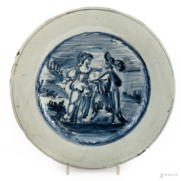 Manifattura Delft del XIX secolo, Piatto in maiolica dipinta nei toni del bianco e del blu con scena galante al cavetto, diametro cm  24, (segni di usura, cadute di smalto, scalfiture, difetti)