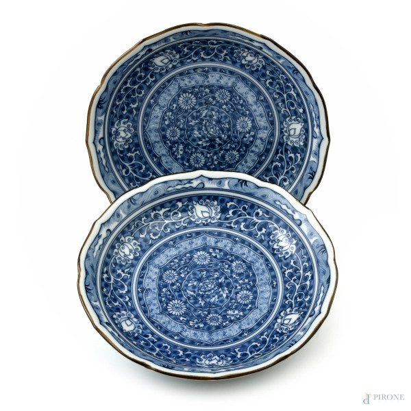 Lotto di due piatti in porcellana decorata nei toni del bianco e del blu a motivi floreali,  diametro cm 20. Cina, XX secolo, (segni di usura)