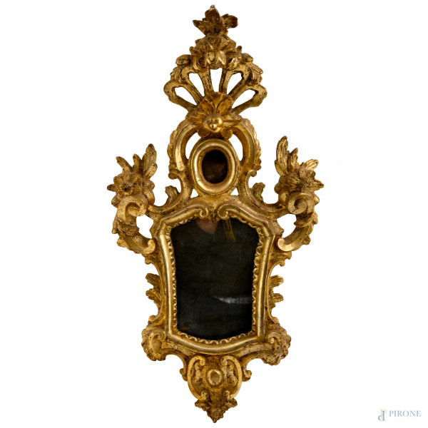 Specchiera in legno intagliato e dorato con specchio al mercurio. Cornice decorata con motivi roccaille, volute e fiori, culminante con cimasa taforata a conchiglia. XIX secolo, cm 75x40, (difetti)