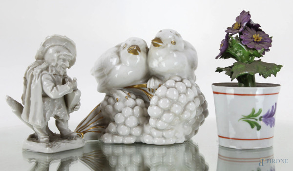 Lotto composto da tre oggetti in porcellana policroma: una coppia di uccellini su grappoli d'uva, una figura di musicista ed un vaso con fiori, manifatture diverse, altezza max cm 11, (difetti).