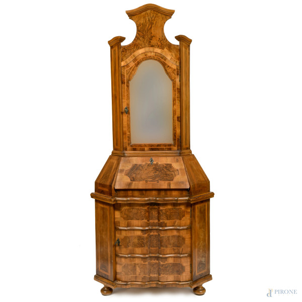 Angoliera in stile Vecchia Verona in legno impiallacciato. Corpo inferiore a fronte mosso a singola anta sormontato da sportello a ribalta. Corpo superiore a singola anta specchiata e sommità sagomata. XX secolo, cm 223x100x60 circa, (segni di usura, scalfiture, sollevamenti di impiallacciatura, difetti)