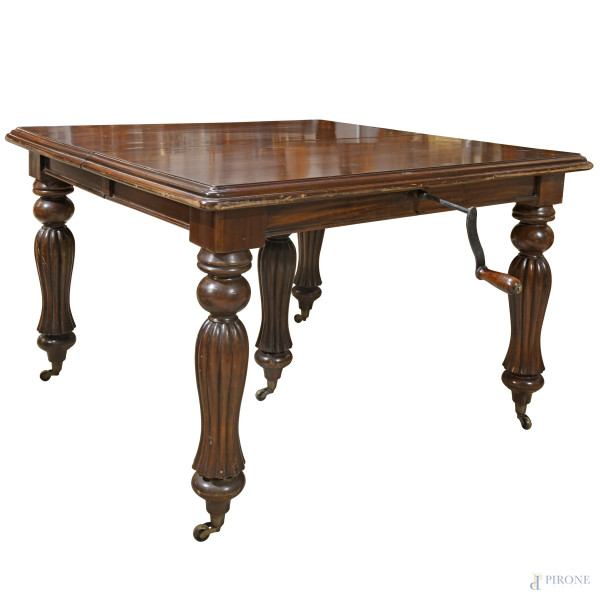 tavolo in mogano allungabile a manovella (3 prolunghe cm 50), con gambe tornite e scanalate su rotelle, XX secolo, cm 83x122x122, (difetti)
