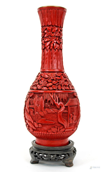 Vasetto in lacca rossa raffigurante personaggi e scene di vita quotidiana rese ad intaglio, cm h 22, arte orientale, inizi XX secolo, poggiante base circolare in legno.